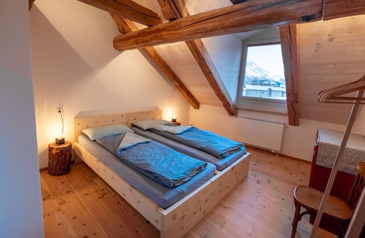 Schlafzimmer der Chesa Tach mit zwei Betten und Blick auf den Piz Mezdi
